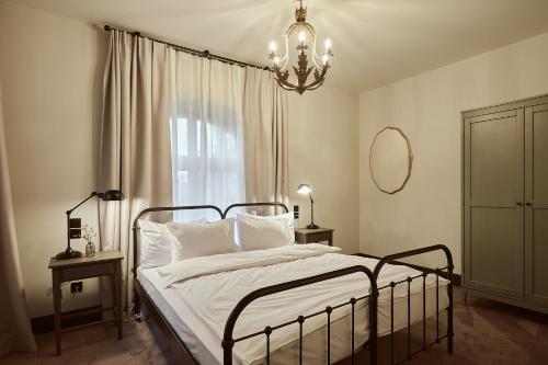 a bedroom with a bed with a chandelier and a window at ARCHE Klasztor Wrocław in Wrocław