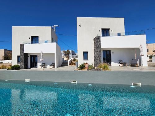 a white house with a swimming pool in front of it at myLithos Suites in Monolithos