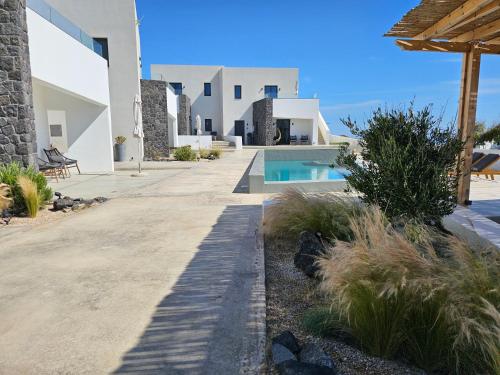 a pathway leading to a villa with a swimming pool at myLithos Suites in Monolithos