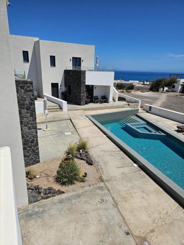 a villa with a swimming pool in front of a house at myLithos Suites in Monolithos