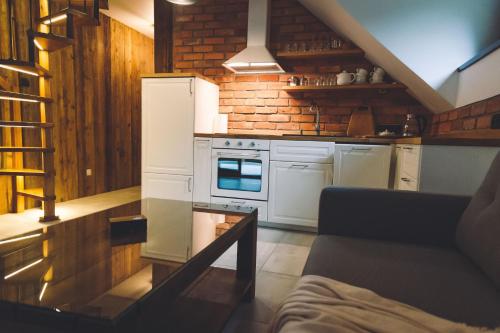 a kitchen with white appliances and a brick wall at LEŚNA STRZECHA APARTAMENTY in Rotembark