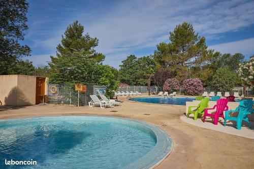 - une piscine avec des chaises colorées à côté de la piscine dans l'établissement Mobil-home 6 personnes chez Vonvon, à La Roque-dʼAnthéron