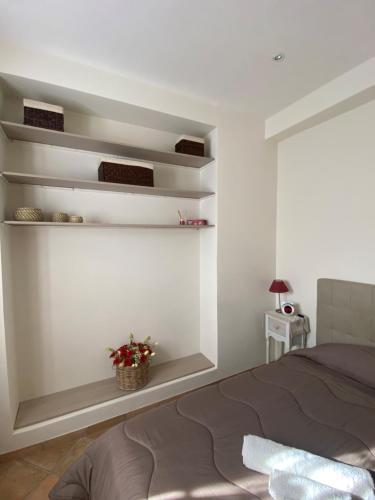 a bedroom with white walls and a bed and shelves at Rhome country lodge in La Massimina-Casal Lumbroso