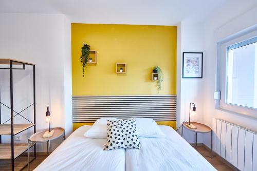 - une chambre avec un lit avec deux tables et un mur jaune dans l'établissement BE-4D - Appartement F3 pour 1-4 pers au 4ème étage au centre de Mulhouse, à Mulhouse
