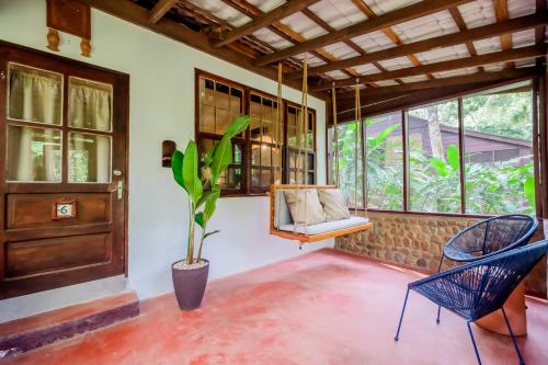 a porch with two chairs and a swing and a plant at Sweet Songs Jungle Lodge in San Ignacio