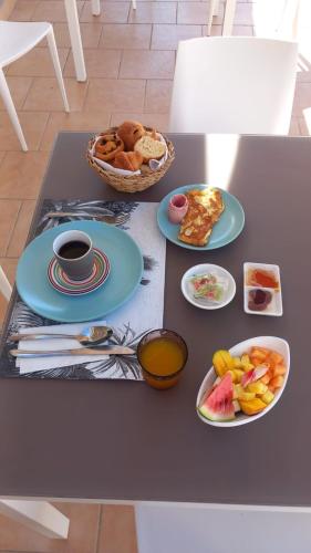 a table with plates of food and a bowl of fruit at Le M Hotel Marie Galante in Beauregard
