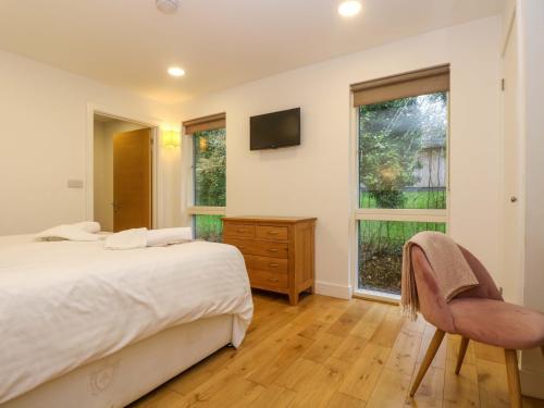 Un dormitorio con una cama y una silla y una ventana. en Juniper, en Truro