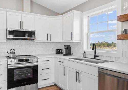a kitchen with white cabinets and a sink and a window at The Perfect Getaway in Bedeque