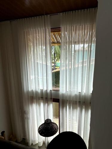 a room with a window with white curtains at Malie Bangalô - Alagoas in Barra de Santo Antônio