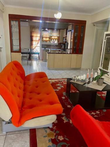 a living room with an orange chair and a table at Жилье целиком in Thessaloniki