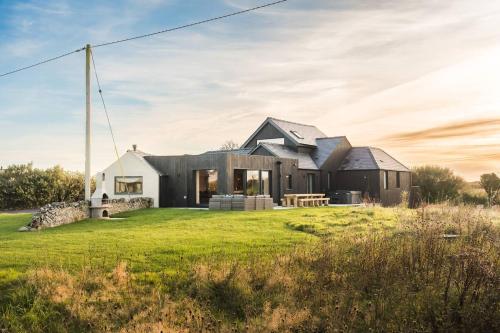 a black house on a grassy field at Alynfa Barn House Rhosniegr in Rhosneigr