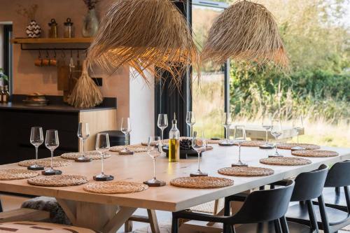 a wooden table with wine glasses and a table at Alynfa Barn House Rhosniegr in Rhosneigr