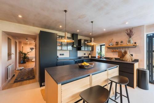 a kitchen with a large island with two bar stools at Alynfa Barn House Rhosniegr in Rhosneigr