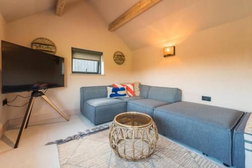a living room with a blue couch and a flat screen tv at Alynfa Barn House Rhosniegr in Rhosneigr