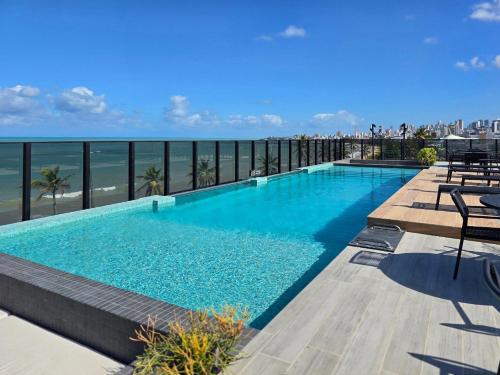 a swimming pool with a view of the ocean at Beach Haus by Hosppedar in João Pessoa
