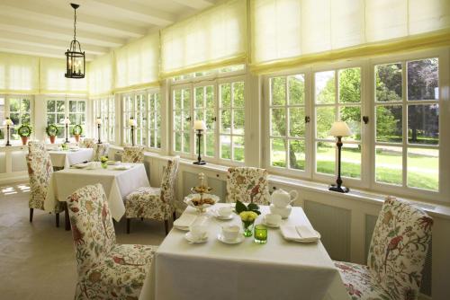 a dining room with tables and chairs and windows at Schlosshotel Münchhausen in Aerzen