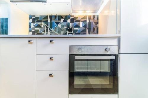 une cuisine avec des armoires blanches et une cuisinière dans l'établissement Magenta, Charmant & Moderne, à Villeurbanne