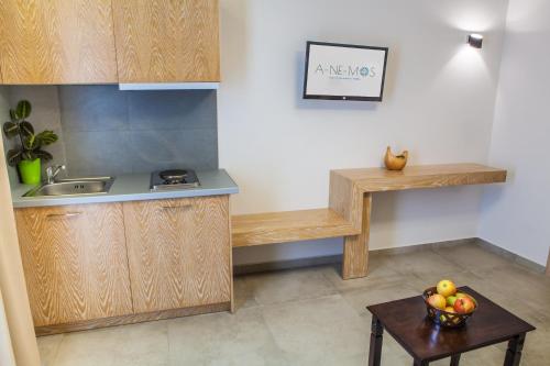 a kitchen with wooden cabinets and a bowl of fruit on a table at Anemos Rooms & Apartments in Nafplio