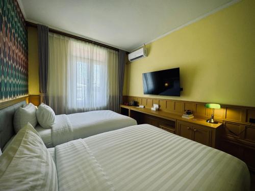 a hotel room with two beds and a flat screen tv at Senglao Boutique Hotel Luang Prabang in Luang Prabang