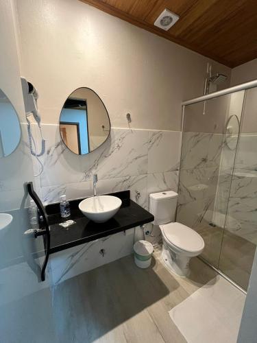 a bathroom with a sink and a toilet and a mirror at Pousada Raízes São Jorge in Sao Jorge