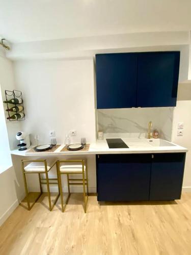 une cuisine avec un comptoir blanc et des armoires bleues dans l'établissement Dijon hyper centre Balnéo Casa Dauphine, à Dijon