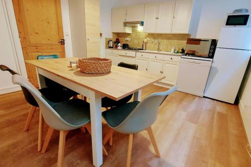 une cuisine avec une table avec des chaises et un réfrigérateur dans l'établissement La Pause Mirepoix - Séjour 3 étoiles, à Mirepoix