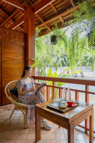 a woman sitting in a chair next to a table at Senglao Boutique Hotel Luang Prabang in Luang Prabang