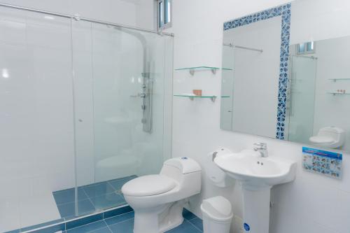 a white bathroom with a toilet and a sink at Hotel Aguamarina in Santa Marta