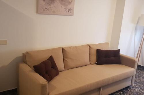 a brown couch with two pillows on it at Vacacional Tegueste 2ºD in Vecindario