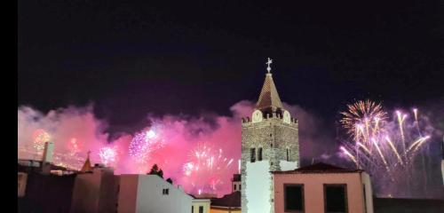 a clock tower with fireworks exploding in the sky at Art House Funchalet in Funchal