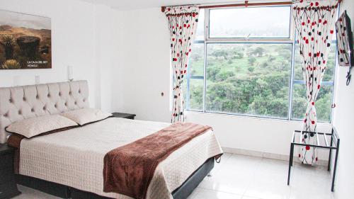 a bedroom with a bed and a large window at Hotel Alta Montaña Mongui By Seres Viajeros in Tópaga