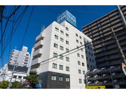 a tall white building in front of two tall buildings at SUIHOKAKU HOTEL - Vacation STAY 49731v in Fukuoka