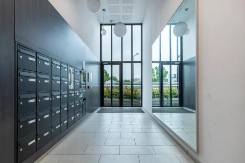 un couloir avec des casiers et une grande fenêtre dans l'établissement Appartement aux portes de Paris, à Aubervilliers