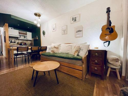 - un salon avec un canapé et une guitare sur le mur dans l'établissement MyHome - Le 44 ! Beau T2 plein centre Val Claret, skis aux pieds, 4 pax, à Tignes