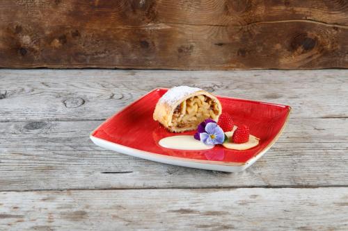 a red plate with a piece of cake and strawberries at Rifugio Ghiacciaio dei Forni in Valfurva