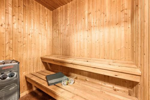 a wooden sauna with a bench and a book at Large Pool House With Activity Room Located In Peaceful Surroundings in Frøstrup
