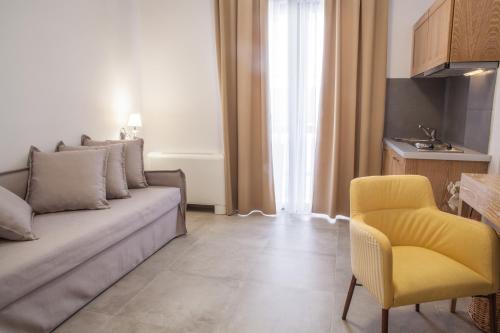a living room with a couch and a yellow chair at Anemos Rooms & Apartments in Nafplio