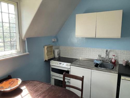 a kitchen with a sink and a stove and a table at Private 1-bedroom apartment in Raynes Park in Raynes Park