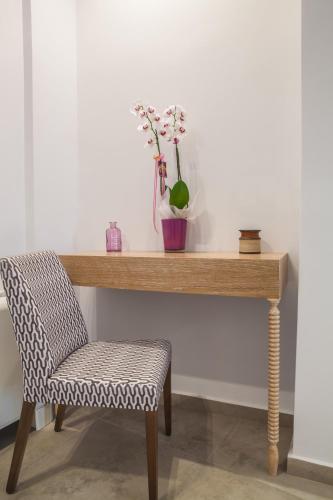 a wooden table with a chair and a vase with flowers at Anemos Rooms & Apartments in Nafplio