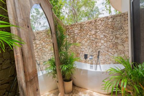 een badkamer met een stenen muur en een bad met planten bij 3BR Villa in Tulum, Pool plus Concierge in Tulum