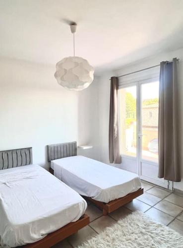 une chambre avec deux lits et une grande fenêtre dans l'établissement Appartement de 2 à 6 personnes 3 chambres proche Aéroport Marseille Marignane -confortable - et tout équipé, à Rognac