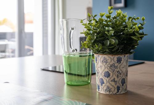 a vase with a plant in it next to a glass at Résidence Léon Blum - Appartements design - Parking in Clermont-Ferrand