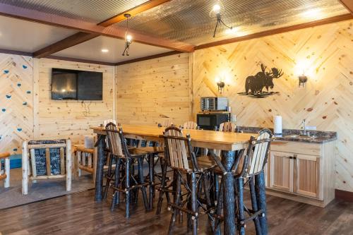 a log cabin kitchen with a large wooden bar with stools at Keweenaw Waters Resort in Houghton