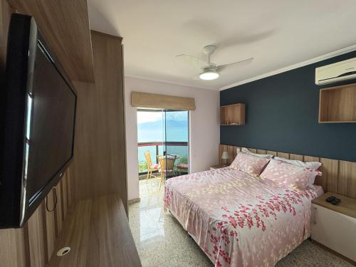 Un dormitorio con una cama y un televisor de pantalla plana. en Apt Pé na Areia - Praia Martim de Sá - Espaço Gourmet na Varanda e Piscina, en Caraguatatuba