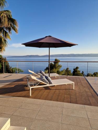 a table with an umbrella and a chair under it at 5 stars 2 bedrooms villa BLUE DREAM village Pisak Croatia in Pisak