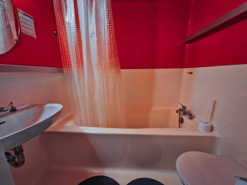 une salle de bain avec une baignoire et un lavabo et des murs rouges dans l'établissement Résidence Lauzieres - Studio 5 personnes skis aux pieds et proche des commerces dans le village du Charvet à Arc 1800 MAE-2194, à Arc 1800