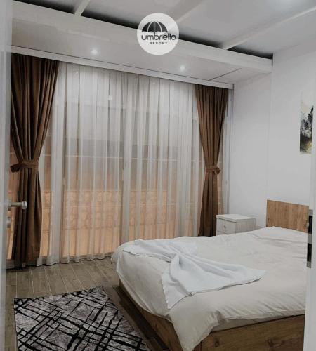a bedroom with a bed and a large window at Umbrella Resort & Villas in Prishtinë