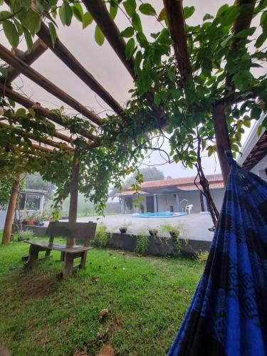 a blue hammock in a yard with a bench at Chácara Cantinho dos Sonhos in Chapada dos Guimarães