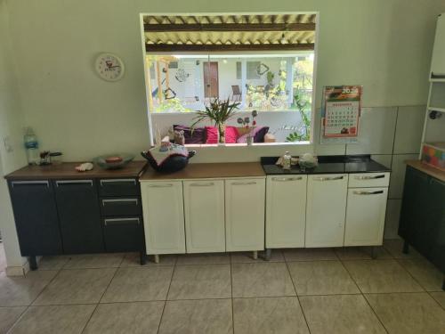 a kitchen with white cabinets and a large window at Chácara Cantinho dos Sonhos in Chapada dos Guimarães