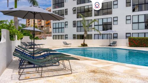 a pool with lounge chairs and an umbrella and a building at Cozy Apartment 2 Bedrooms Amenities in Acapulco